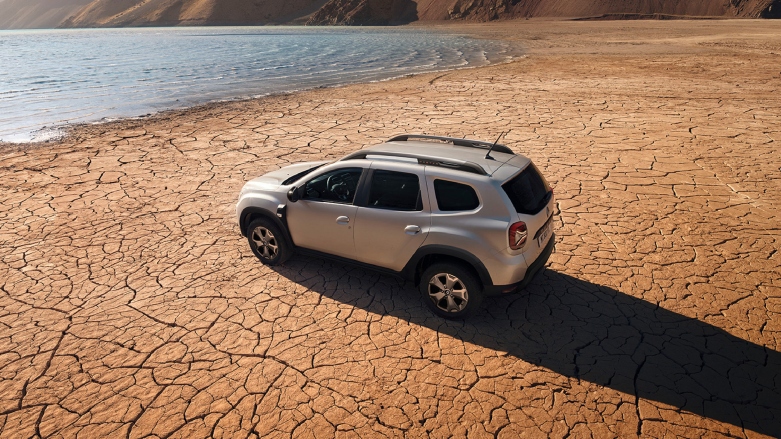 Renault Duster 2025 Gris Casiope en terreno rocoso con fondo de paisaje natural.